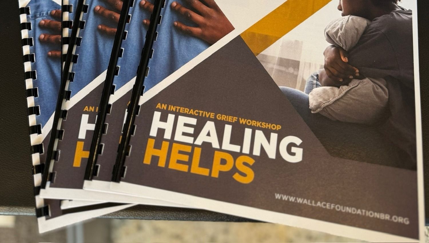 Bound Healing Helps workbooks stacked on a table, titled “An interactive grief workshop”.