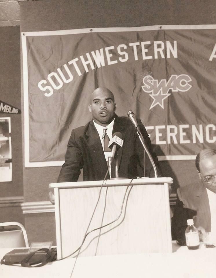 Coach Sean Wallace speaking at a podium in front of a Southwestern Athletic Conference banner